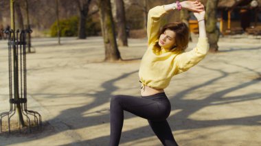 Genç esmer kadın şehir parkında esneme egzersizleri yapıyor.. 