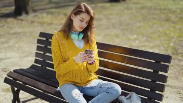 Gadis Muda Dengan Headphone Menggunakan Telepon Taman Kota — Stok Video