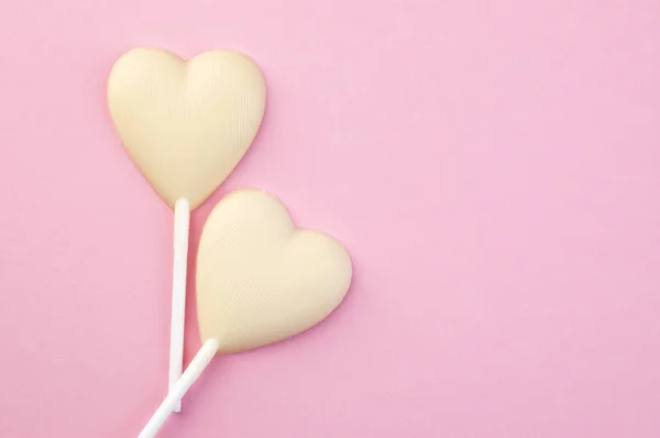 Два белых шоколадных сердечка на розовом — стоковое фото