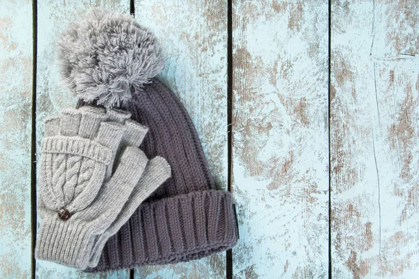 Pletené čepice a rukavice na dřevěné pozadí — Stock fotografie