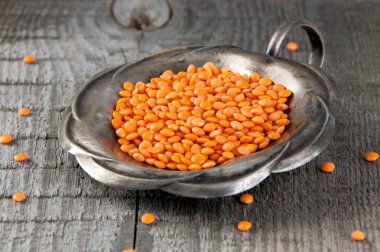 Vintage gümüş kavanoz eski ahşap arka plan üzerinde kırmızı mercimek.