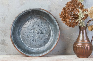 Beton zeminde antik bakır elek.