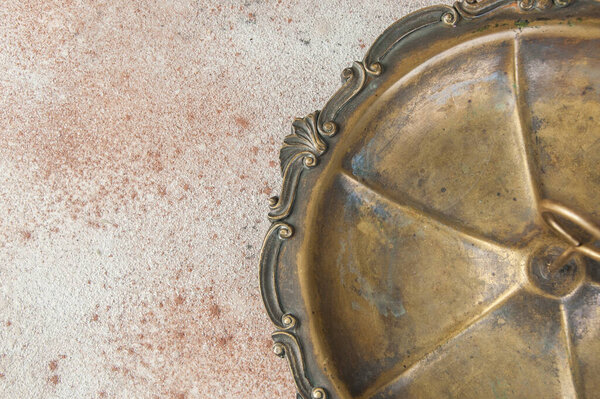 Античная латунь, подающая блюдо с кольцевой ручкой для десертов или закусок с чаем на бетонном фоне. Фотореквизит и копировальное место для текста

