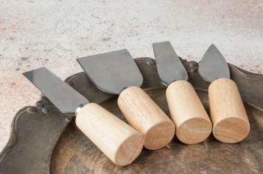 Eski peynir bıçakları, ahşap sapları ve beton arka planda eski metal kaplar. Metin ve yemek fotoğrafçılığı için boşluk kopyala.