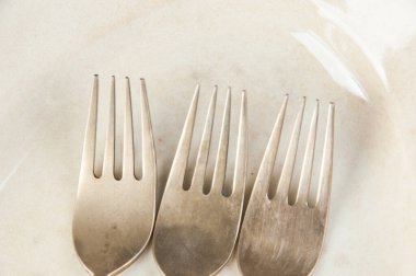 Beton arka planda antika oval plaka üzerinde üç eski bronz çatal. Metin ve yemek fotoğrafçılığı için boşluk kopyala.