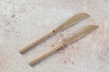 Beton arka planda iki bronz bıçak. Metin ve yemek fotoğrafçılığı için boşluk kopyala.