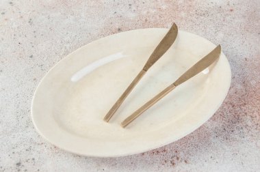 Beton zeminde oval plaka üzerine eski bronz bıçaklar. Metin ve yemek fotoğrafçılığı için boşluk kopyala.