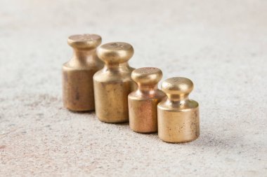 Beton arka planda pullar için dört antika bronz ağırlık. Metin ve yemek fotoğrafçılığı için alanı kopyala.