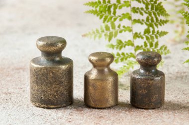 Beton arka planda pullar için üç antika bronz ağırlık. Metin ve yemek fotoğrafçılığı için alanı kopyala.