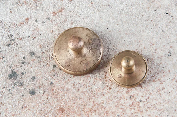 Two antique bronze weights for scales on concrete background. Copy space for text and food photography props.