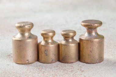 Beton arka planda pullar için dört antika bronz ağırlık. Metin ve yemek fotoğrafçılığı için alanı kopyala.