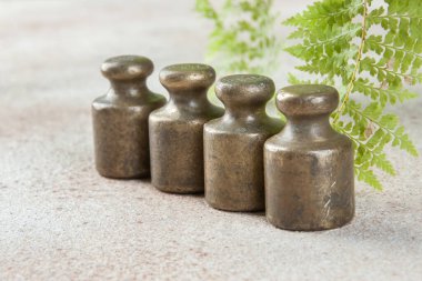 Beton arka planda pullar için dört antika bronz ağırlık. Metin ve yemek fotoğrafçılığı için alanı kopyala.