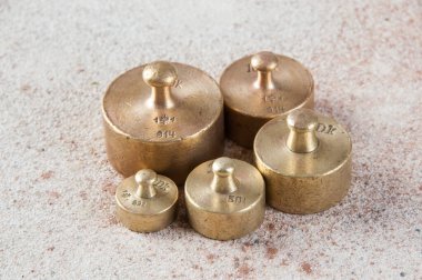 Beton arka planda pullar için beş antika bronz ağırlık. Metin ve yemek fotoğrafçılığı için alanı kopyala.