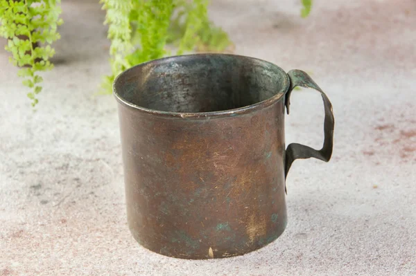 Old military brass mug with handle on concrete background. Copy space for text, photography props