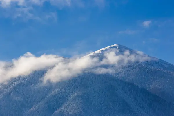 Neve coberto belos picos de montanha e nuvens brancas suaves em b — Fotografia de Stock