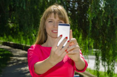 Kız selfie doğa üzerinde yapar.