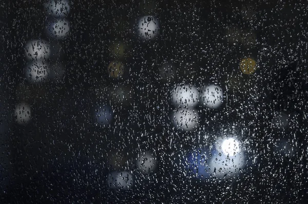 Gouttes de pluie sur la fenêtre sur le fond du bokeh de nuit — Photo