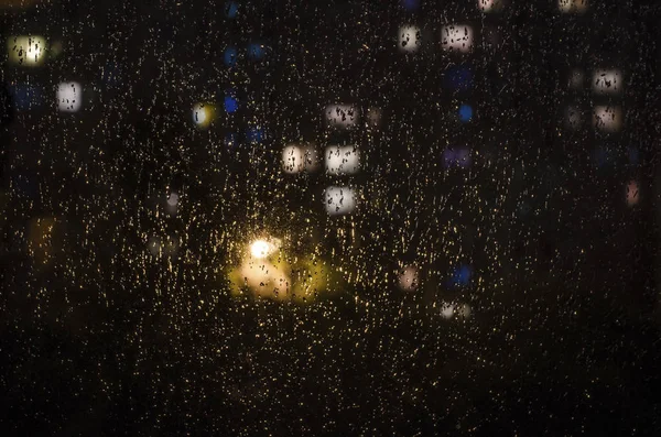 Gocce di pioggia sulla finestra sullo sfondo del bokeh notte — Foto Stock