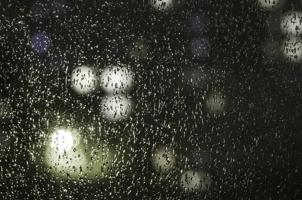 Regentropfen auf dem Fenster auf dem Hintergrund des Nachtbokeh — Stockfoto