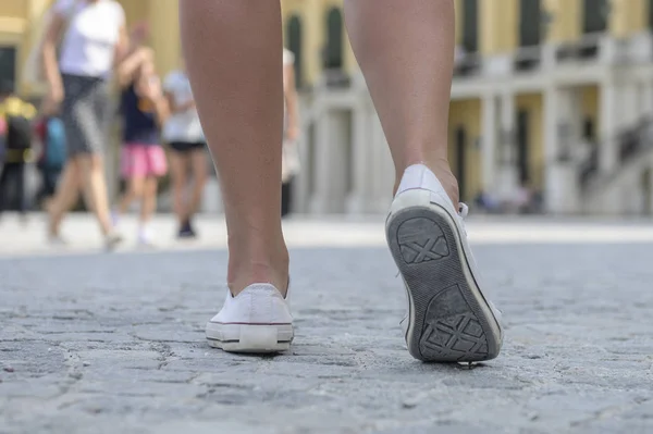 Primer plano de las piernas femeninas con zapatillas blancas —  Fotos de Stock