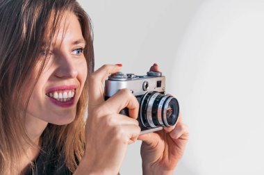 Uzun saçlı kadın retro kamerayla fotoğraf çekiyor.