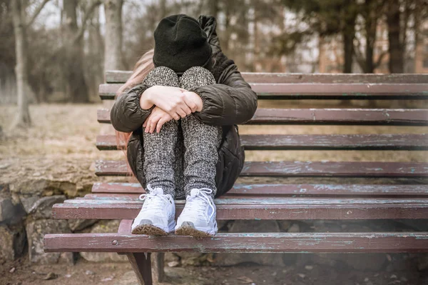 Triste ragazza depressa seduta su una panchina in un parco — Foto Stock