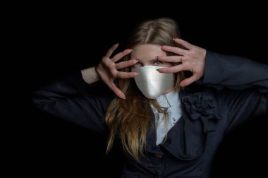Tıbbi maske, koronavirüs ve diğer virüslere karşı koruma. Siyah takım elbiseli kadın siyah arka plandaki kameraya bakıyor.