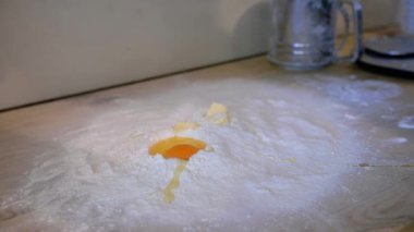 Tavuk sarısı unun içine düşer. Yumurta sarısı un yığınına eklenir, ağır çekimde.