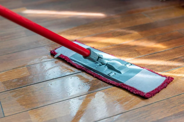 A mop washing a wooden floor in an apartment. Concept of care for the cleanliness of the apartment. Mopping the floor