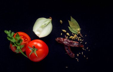 Siyah arka planda domates, soğan ve baharatlar