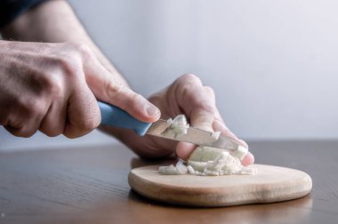 Adam mutfakta bıçakla soğan doğruyor.