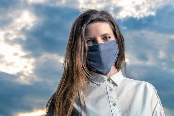 Tıbbi maske, koronavirüs ve diğer virüslere karşı koruma. Dramatik bir gökyüzüne karşı bir kadın portresi