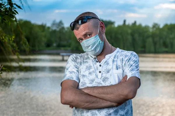Tıbbi maske, koronavirüs ve diğer virüslere karşı koruma. Gölün arka planında bir adamın portresi