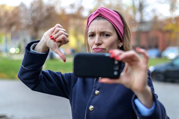 young cheerful woman loudly on the video call of the phone on the street