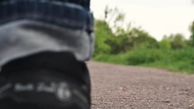 Spor ayakkabılı adam toprak yolda yürüyor. Kot pantolon ve spor ayakkabı giymiş bir çocuk parkta yürüyor. Kapalı bacaklar, yürüyen bir adam.