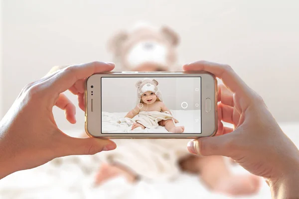 Kadın bebeğinin fotoğrafını cep telefonuyla çekiyor. Akıllı telefonun fotoğraf makinesi..