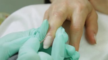 Lateks eldivenli profesyonel manikürcü, tırnak makası kullanarak manikür yapan, kuafördeki ya da evdeki tırnak derisini düzelten kadın müşteriyi öğütüyor. Yakın çekim gerçek zamanlı görüntü