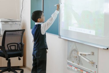 School. The boy in school uniform writes on an interactive whiteboard. clipart