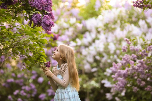 Mooi Jong Meisje Zoek Naar Lila Bloemen Lente Tuin Blond — Stockfoto