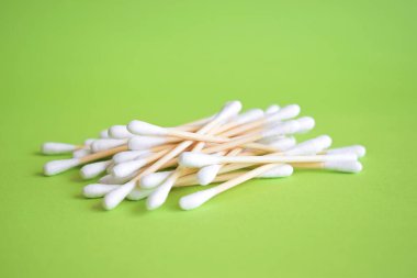  Renkli yeşil arka planda beyaz pamuklu kulaklıklar. Yakın çekim.