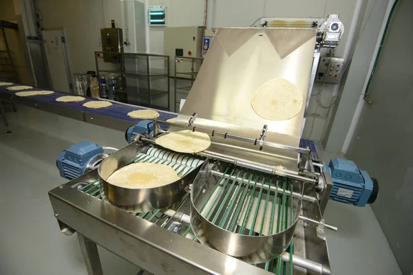 Pizza dough running on conveyor belt