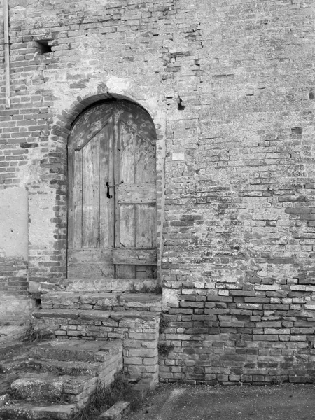 Puerta de madera vieja en la pared de ladrillo viejo. Foto en blanco y negro — Foto de Stock