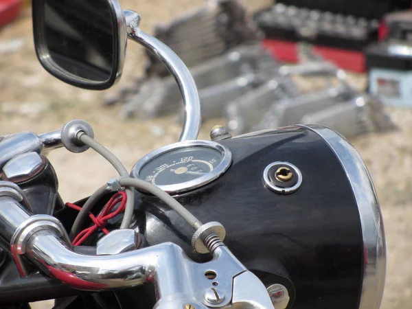 Retro motocykl stojí na silnici. Detailní záběr reflektoru motocyklu, rychloměru a jízdního zrcátka Stock Fotografie