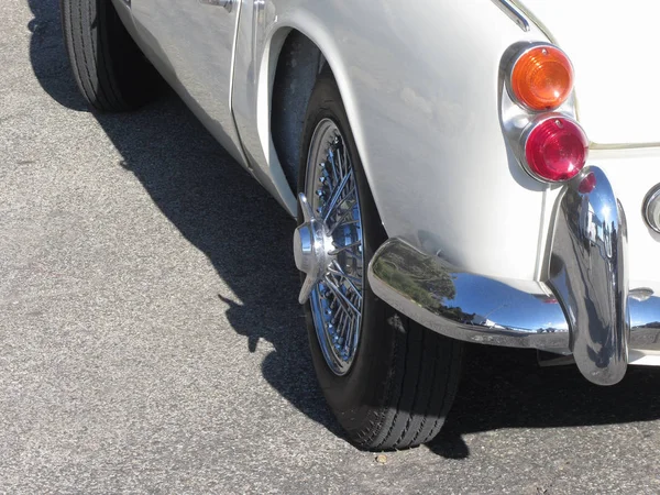 La parte trasera de un viejo coche clásico británico. Vista particular de la luz trasera izquierda, parachoques cromado brillante y neumático trasero izquierdo. El coche es un modelo Triumph TR3 producido entre 1955 y 1962 — Foto de Stock