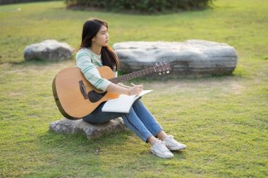 genç kadın alanında oturup ve gitar çalmak