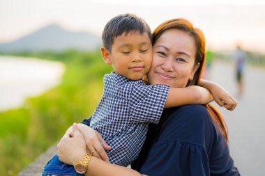 Asya anne sarılmak genç oğlu sevgiyle doğa backg ile gün batımında