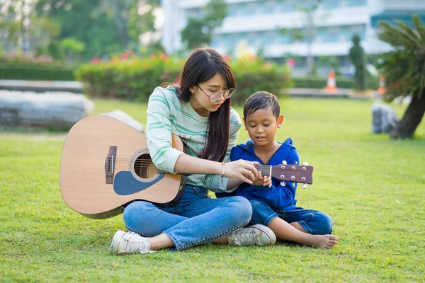 Asiática adolescente ensinar guitarra para o menino com carinho e fu — Fotografia de Stock