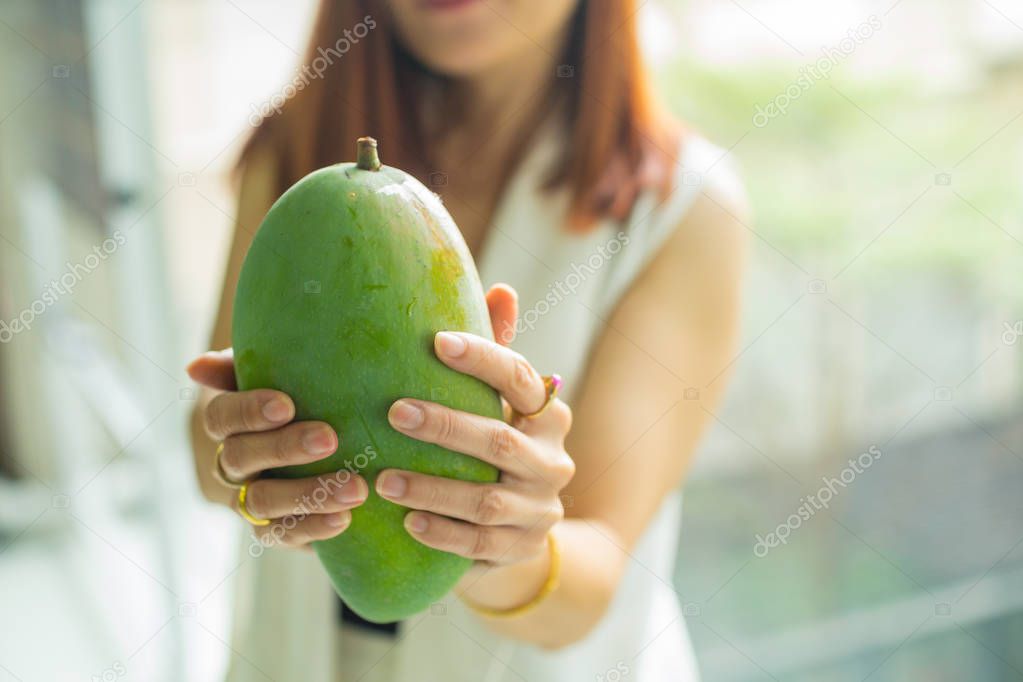 woman holding a fresh Mango in her hand and blur of woman