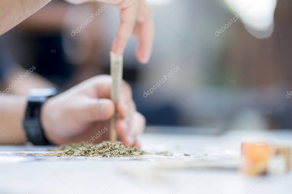 Heap of cannabis And the blur of the man's hand is rolling the c