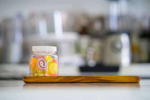 colorful sweet jelly candies in bottle on wooden plate at coffee shop